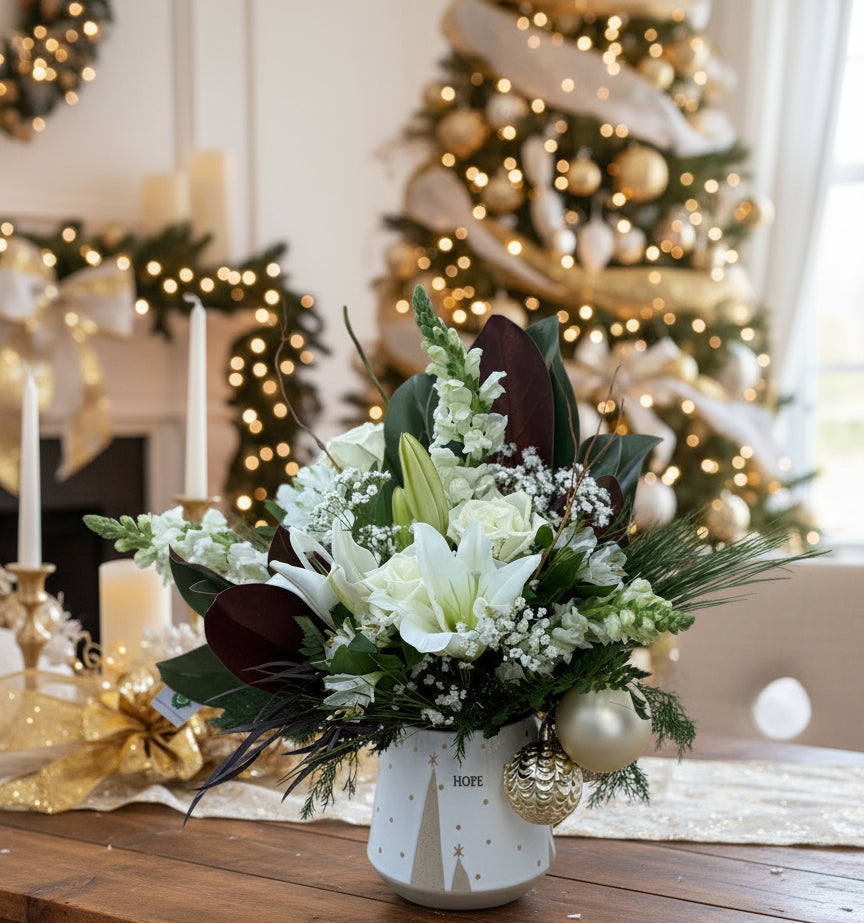 Floral arrangement with white flowers and green leaves in a decorative pot.