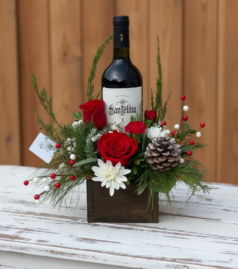 Wine bottle in a decorative floral arrangement with red roses and greenery on a neutral background